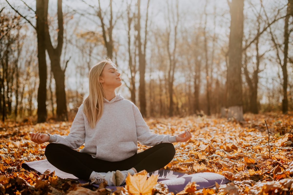 girl in autumn forest on yoga mat