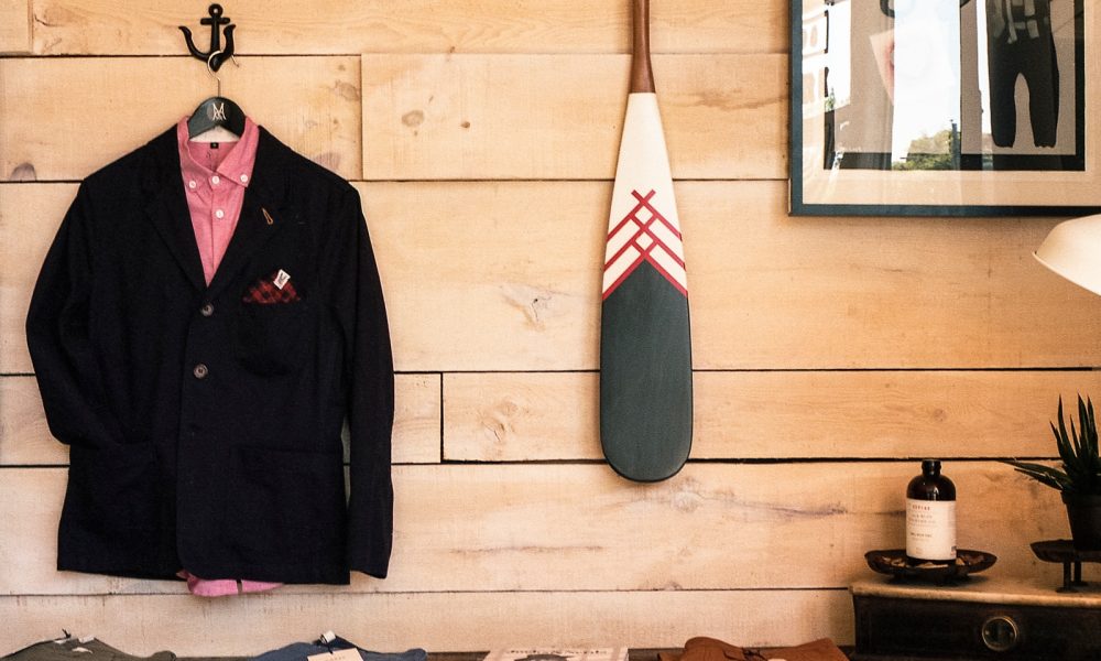 black jacket hanging on brown wooden wall beside boat paddle