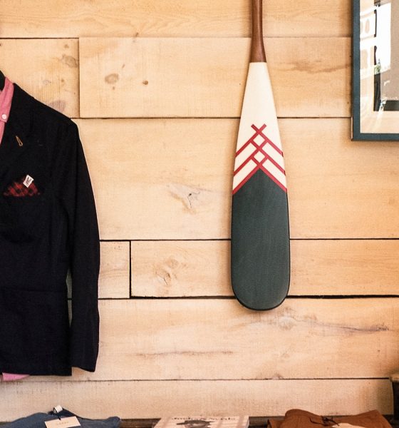 black jacket hanging on brown wooden wall beside boat paddle